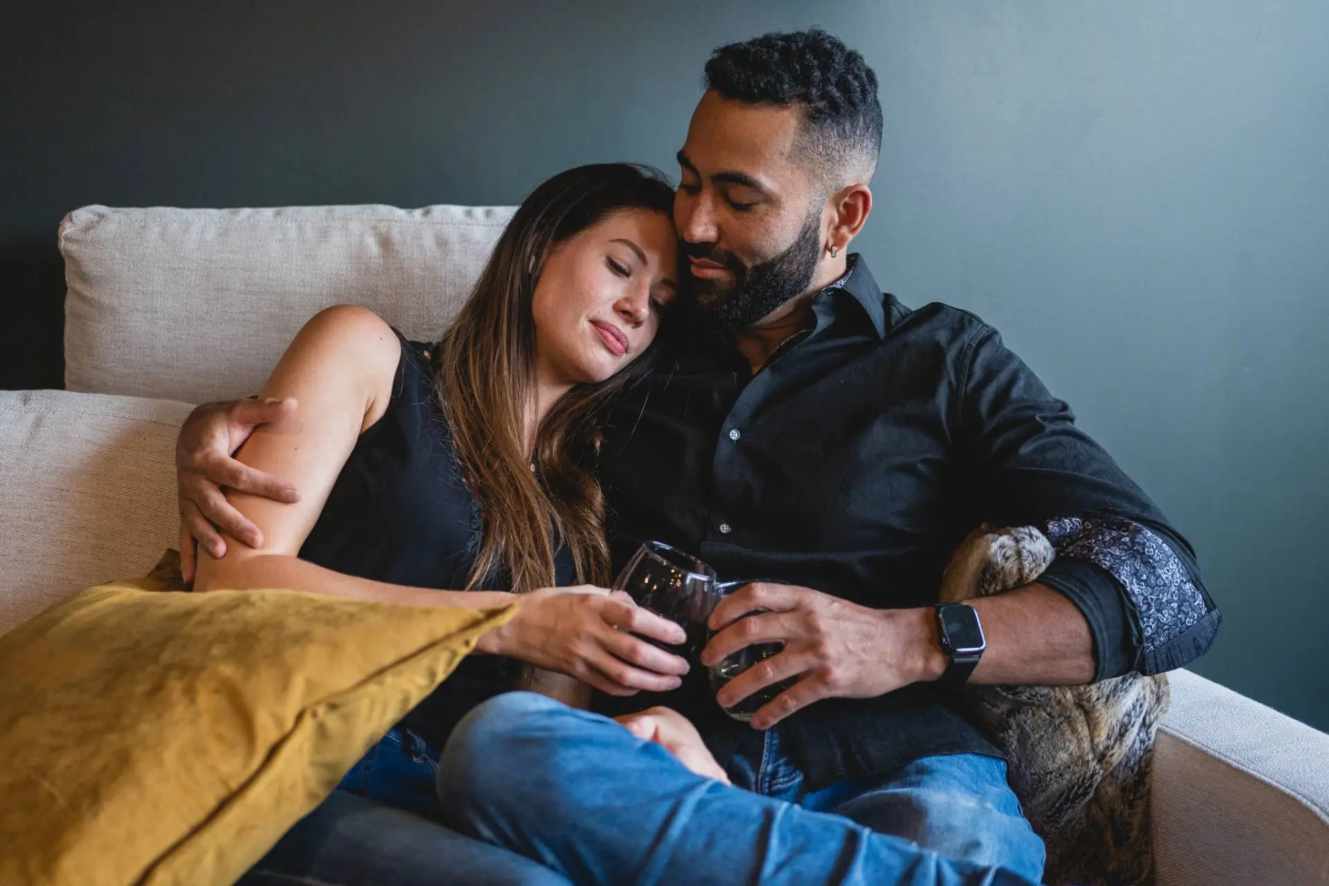 Couple relaxing together on a sofa with drinks.
