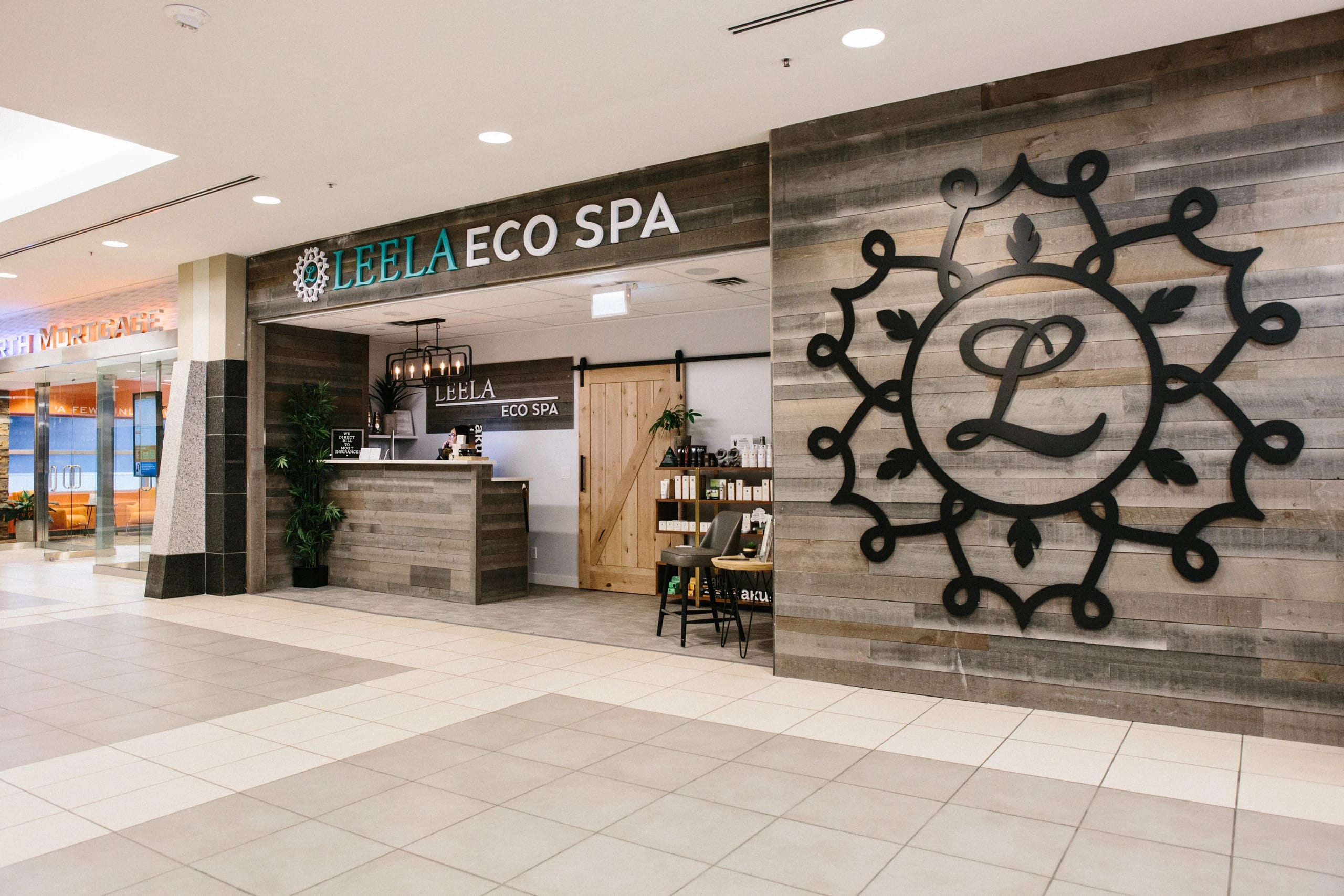 The Calgary Place Leela Eco Spa mall storefront with wood façade and brand signage.