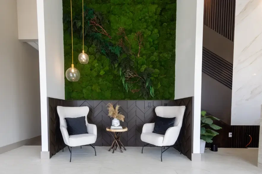 Reception lounge at Leela Eco Spa Carrington — white wingback chairs against a living moss wall.
