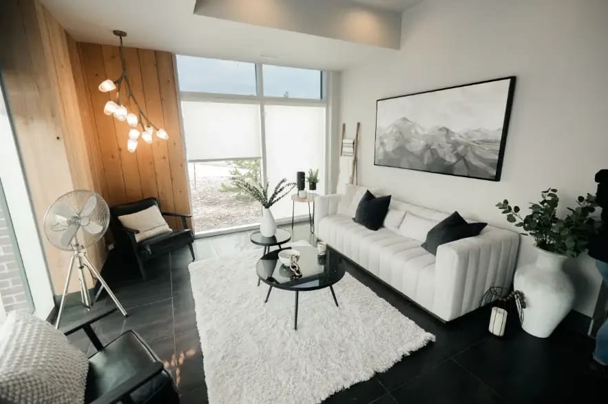 Reception lounge at Leela Eco Spa Legacy Township — white tufted sofa, black chairs, and a wood-panel feature wall.