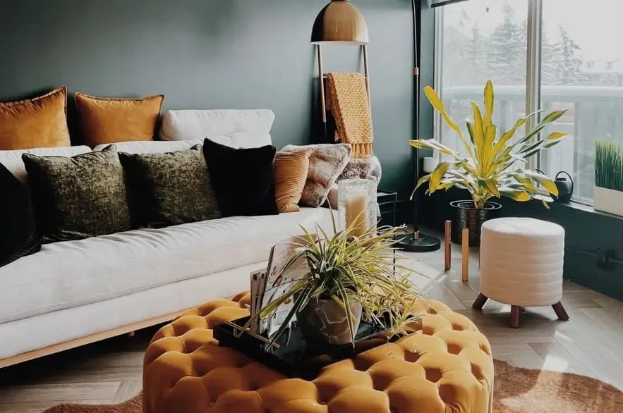 Reception lounge at Leela Eco Spa Marda Loop — cream sofa, mustard ottoman, and emerald green walls.