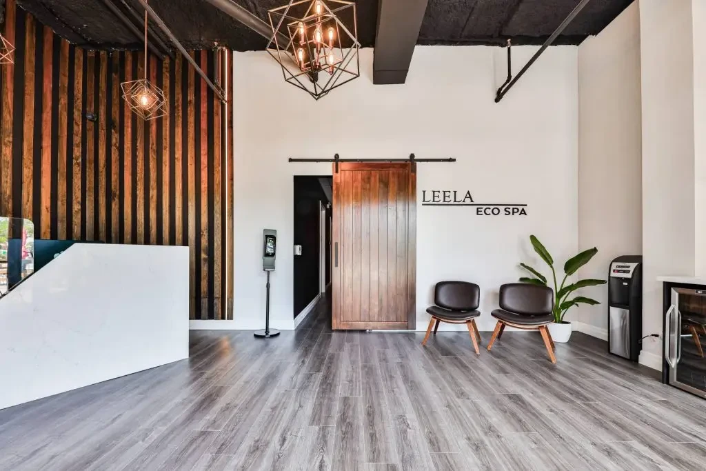 Reception at Leela Eco Spa Town Square Oakville — wood-slat wall, barn door, and LEELA ECO SPA lettering.