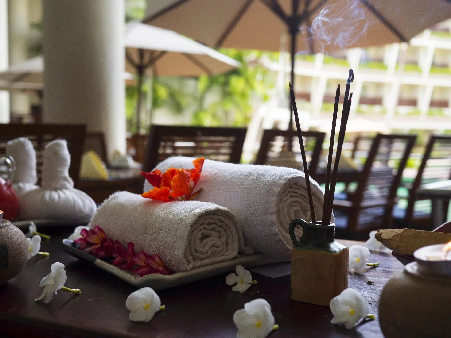 Rolled spa towels with flowers and incense.