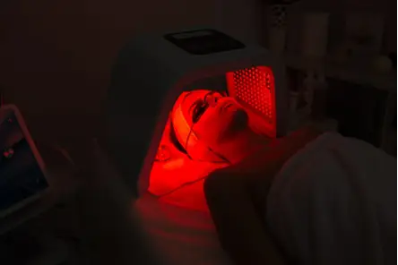 Client receiving red LED light therapy under a treatment lamp.