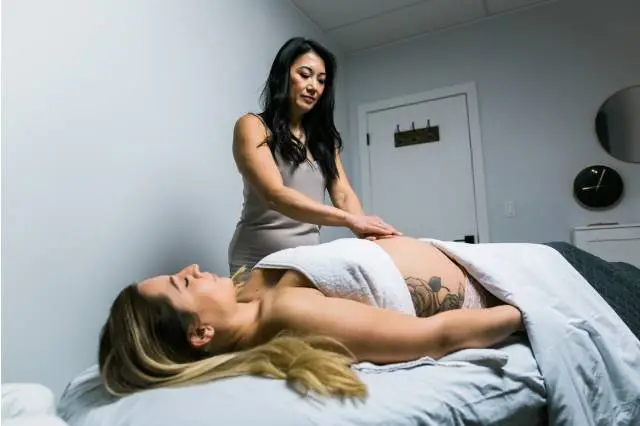 Therapist massaging a client’s back on a treatment table.