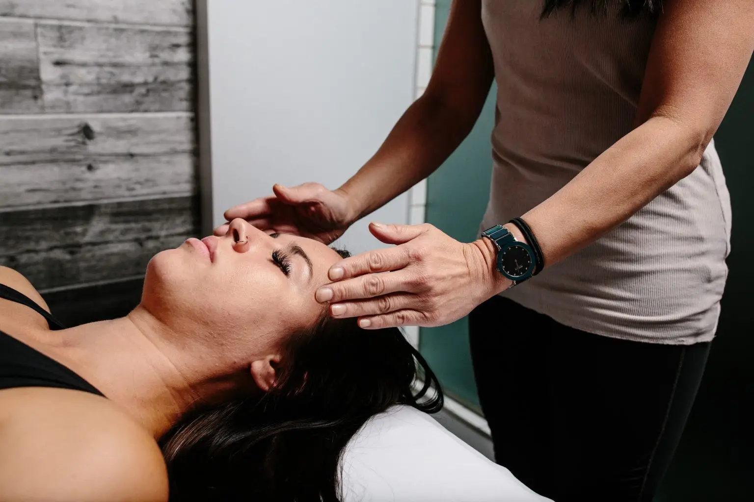 Therapist massaging a client’s neck and shoulders on a treatment table.